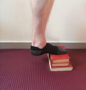 Image d'un homme en équilibre, l'avant du pied à plat sur un tas de livre